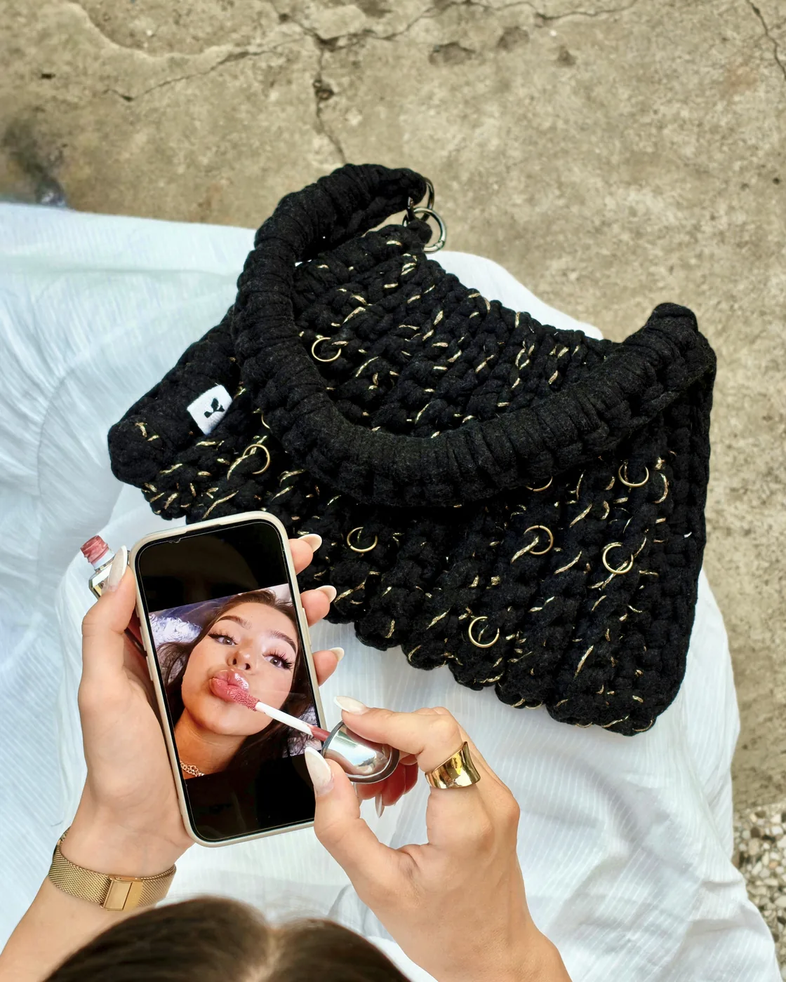 Black Golden Noir crochet bag with brass rings, on white cloth